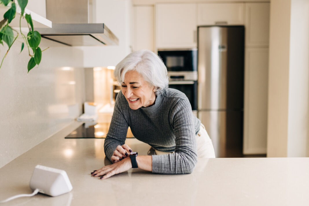Senior woman using smart devices in her kitchen at home